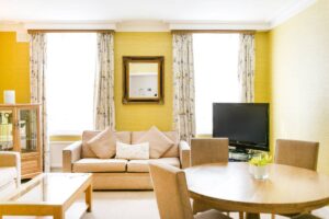 A living room with yellow walls, a sofa, a dining table and a television