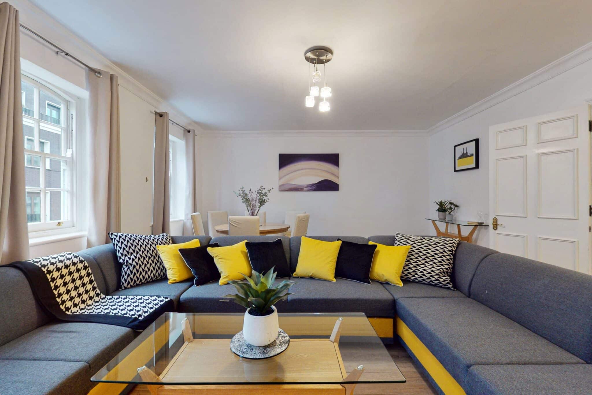 Living room with a large grey corner sofa and a glass coffee table at 34-36 Clarges Street Mayfair