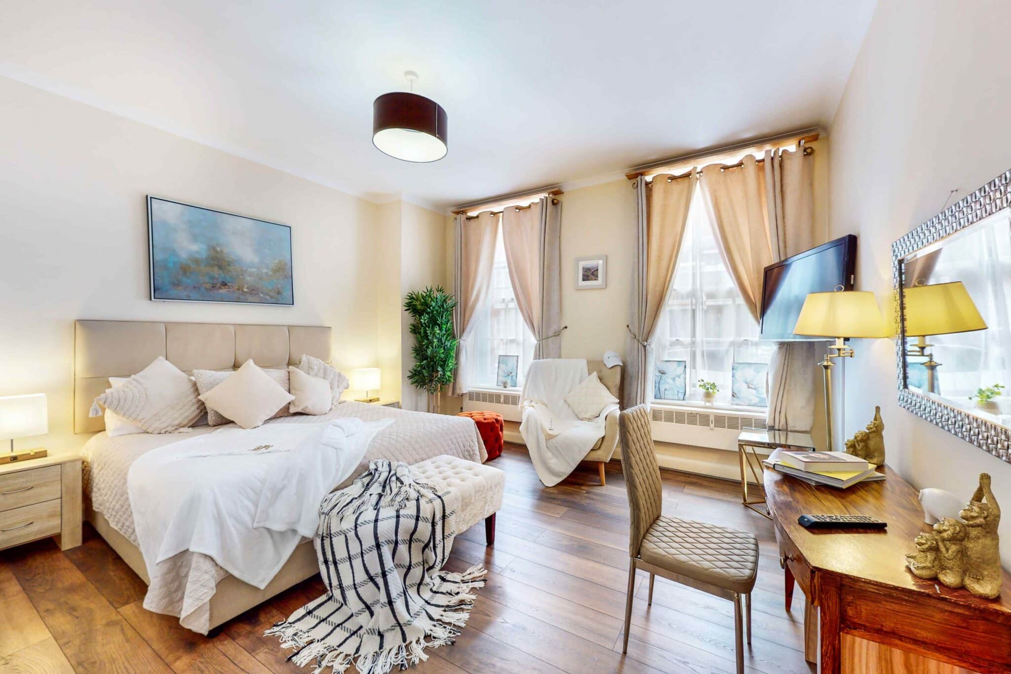 Double bedroom with tall curtained windows at Shaw House Mayfair