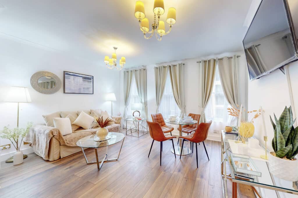 Sitting and dining room with a cream sofa and orange dining chairs at Mayfair Collection 37 Clarges Street