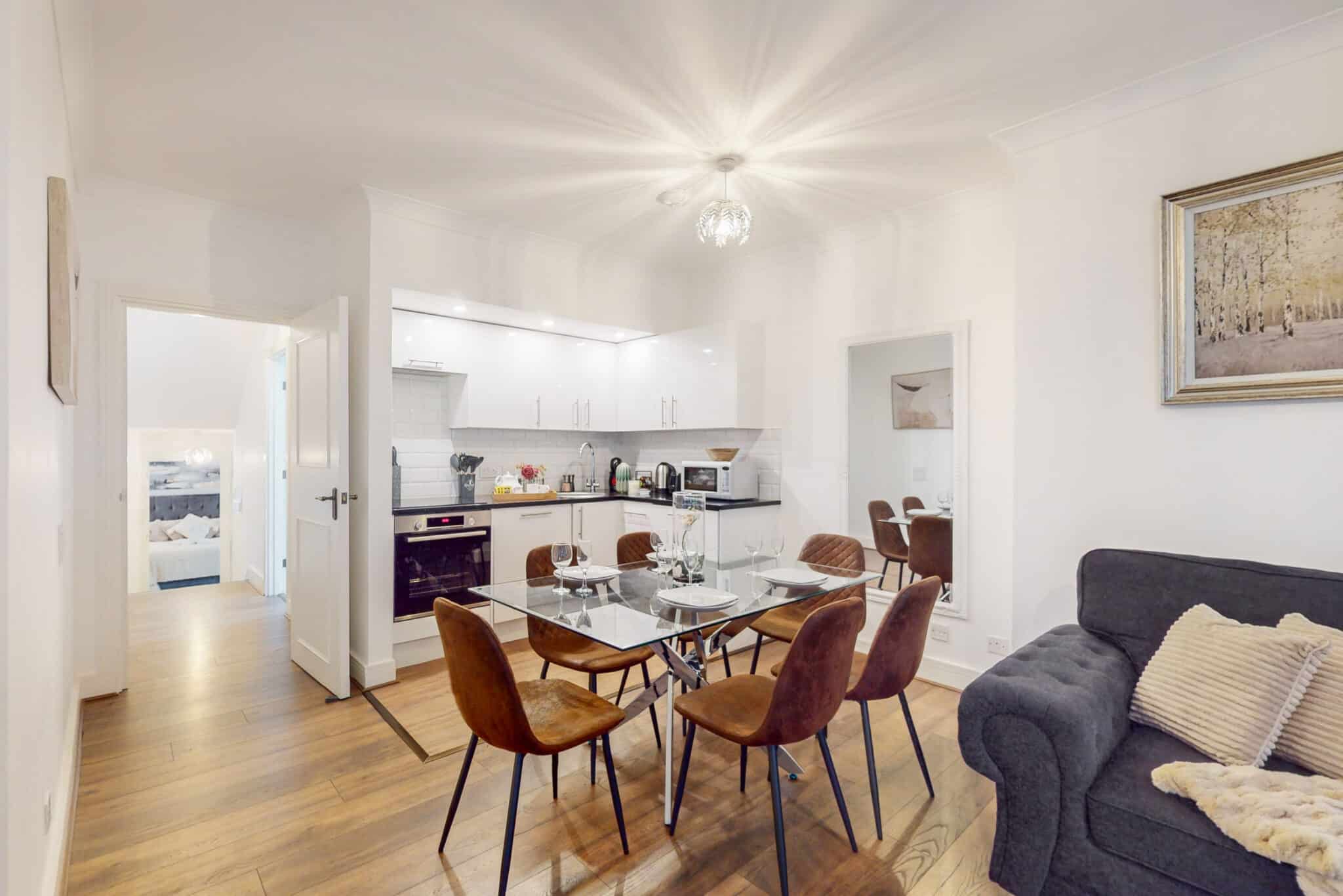 Open plan kitchen and dining area with wooden chairs at 34-36 Clarges Street Mayfair