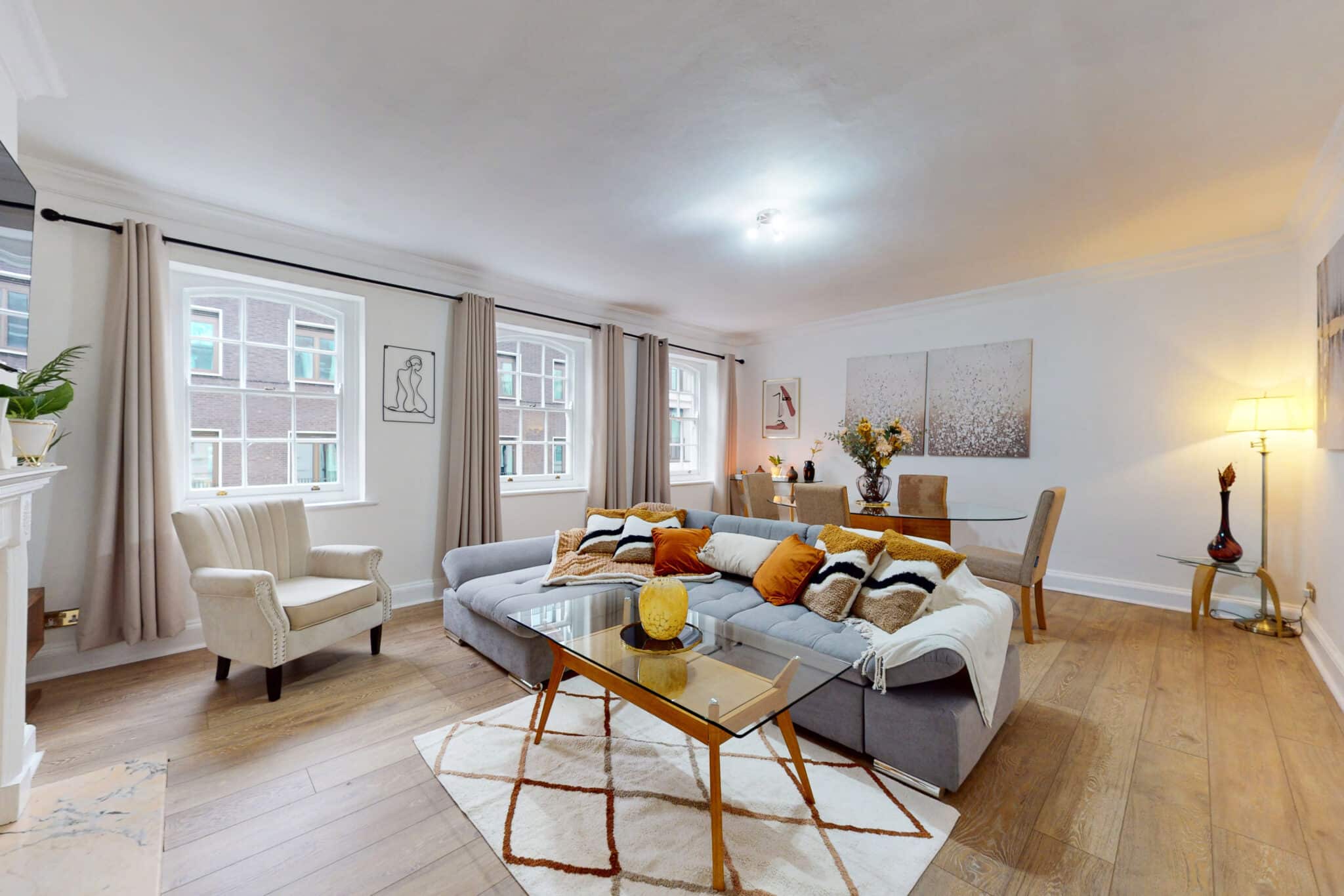 Living room with a grey corner sofa and two tall windows at 34-36 Clarges Street Mayfair