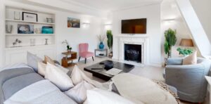 A living room with a grey corner sofa, a wall-mounted television and house plants