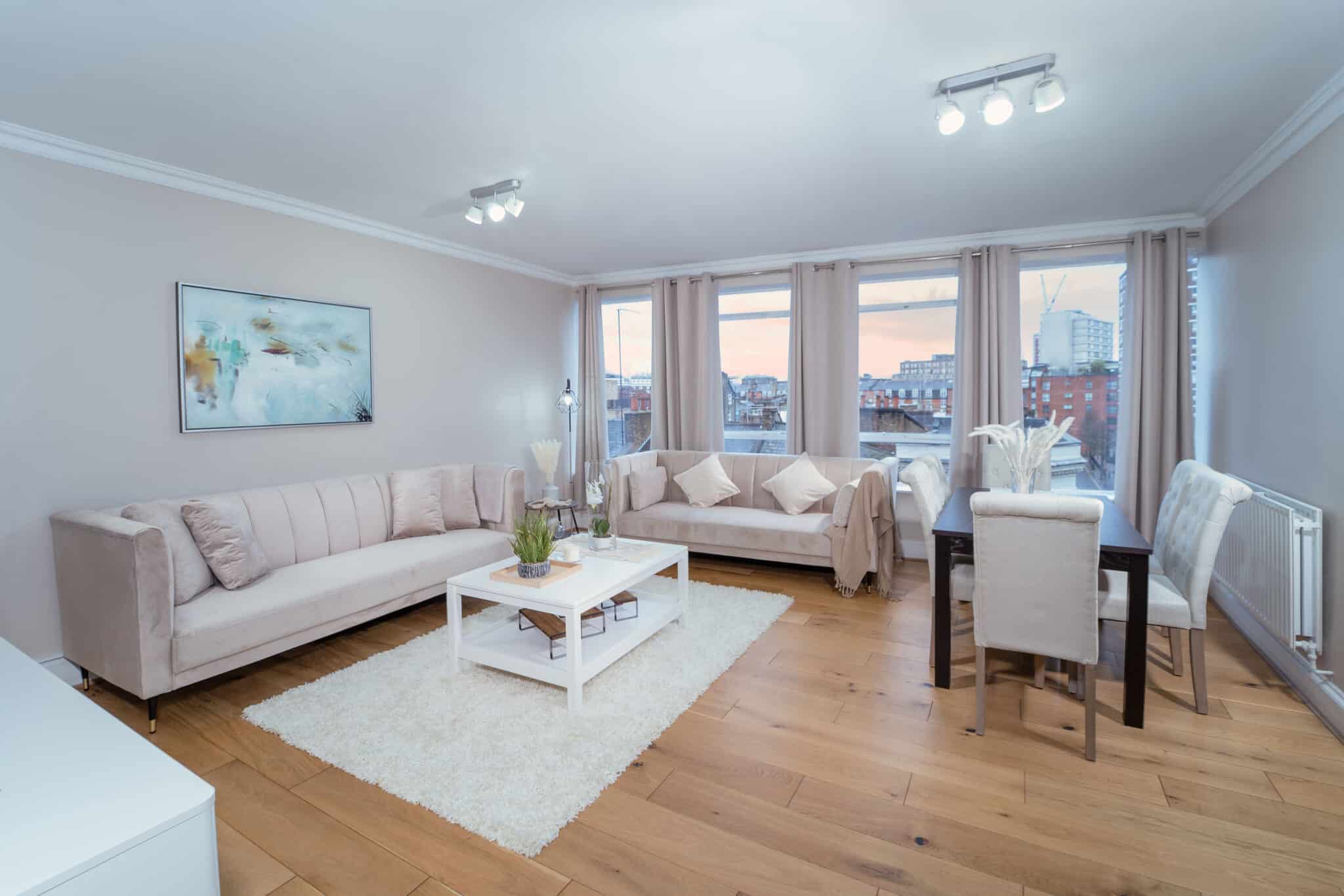 Living and dining room with pale sofas and a rooftop view at dusk at Crawford Place Marylebone