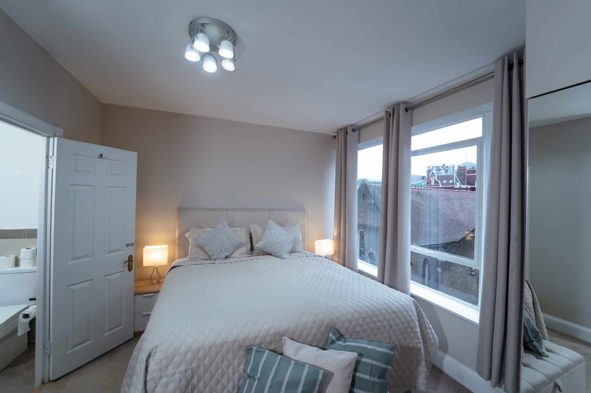 Double bedroom with a tall curtained window at Crawford Place Marylebone