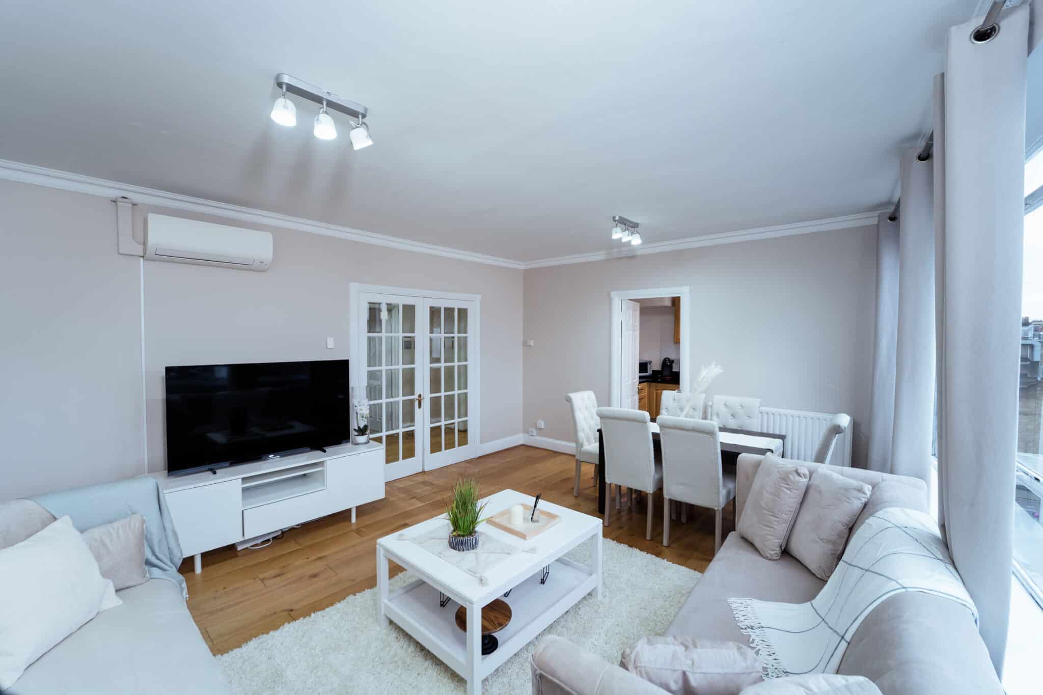 Living room with a wall mounted television and glazed doors through to the dining room at Crawford Place Marylebone