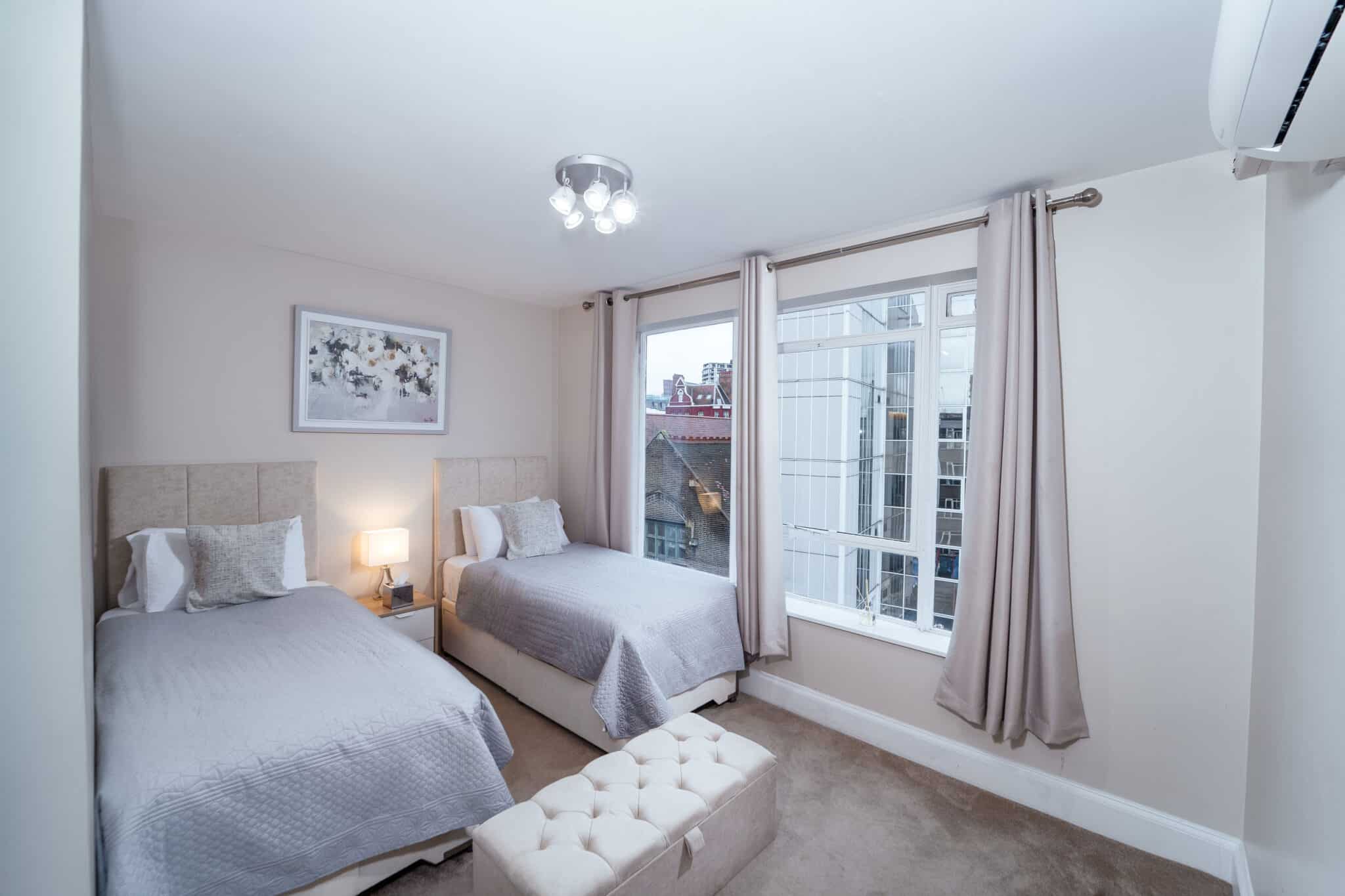 Twin bedroom with two single beds and a tall window at Crawford Place Marylebone