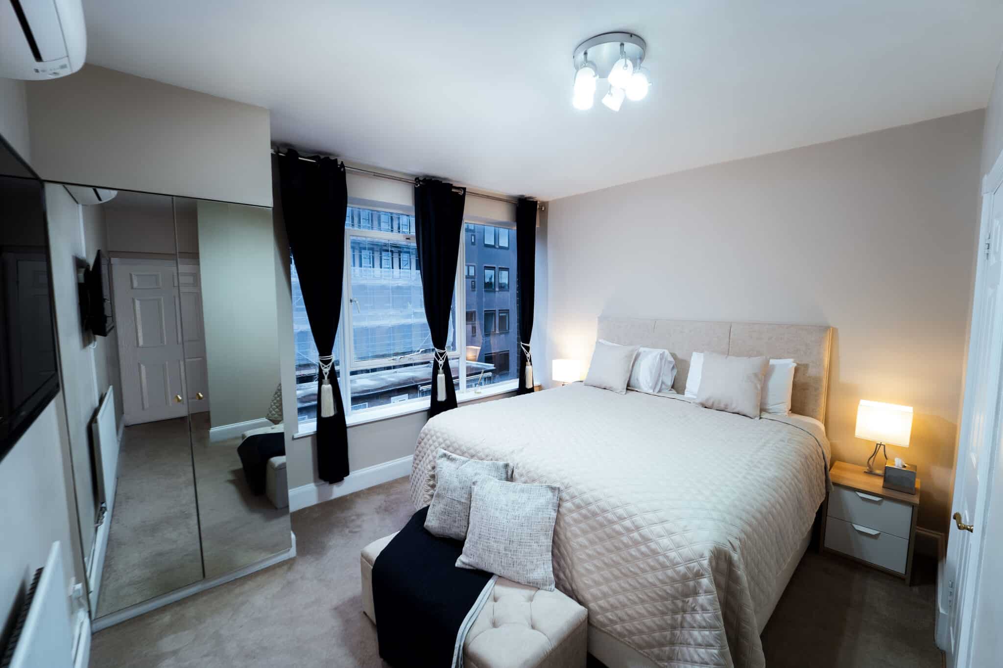 Double bedroom with mirrored wardrobe doors and bedside lamps at Crawford Place Marylebone