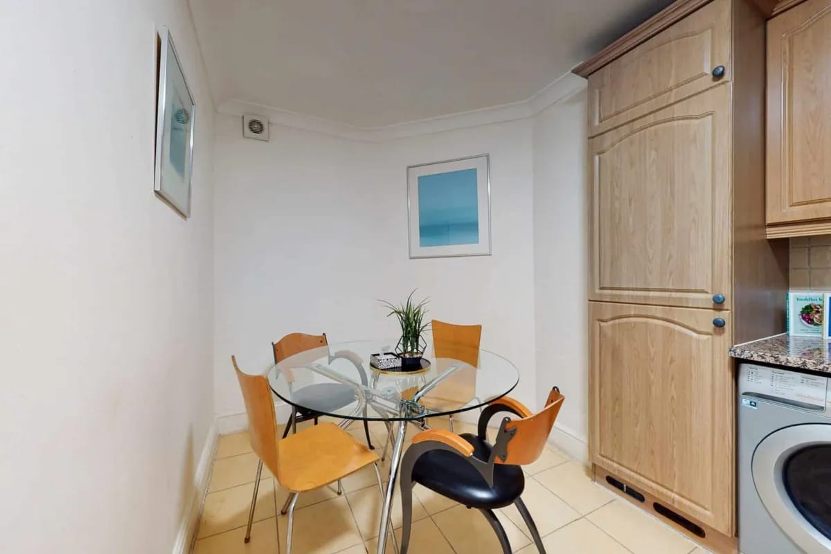 Open plan kitchen and dining area with wooden chairs at 34-36 Clarges Street Mayfair