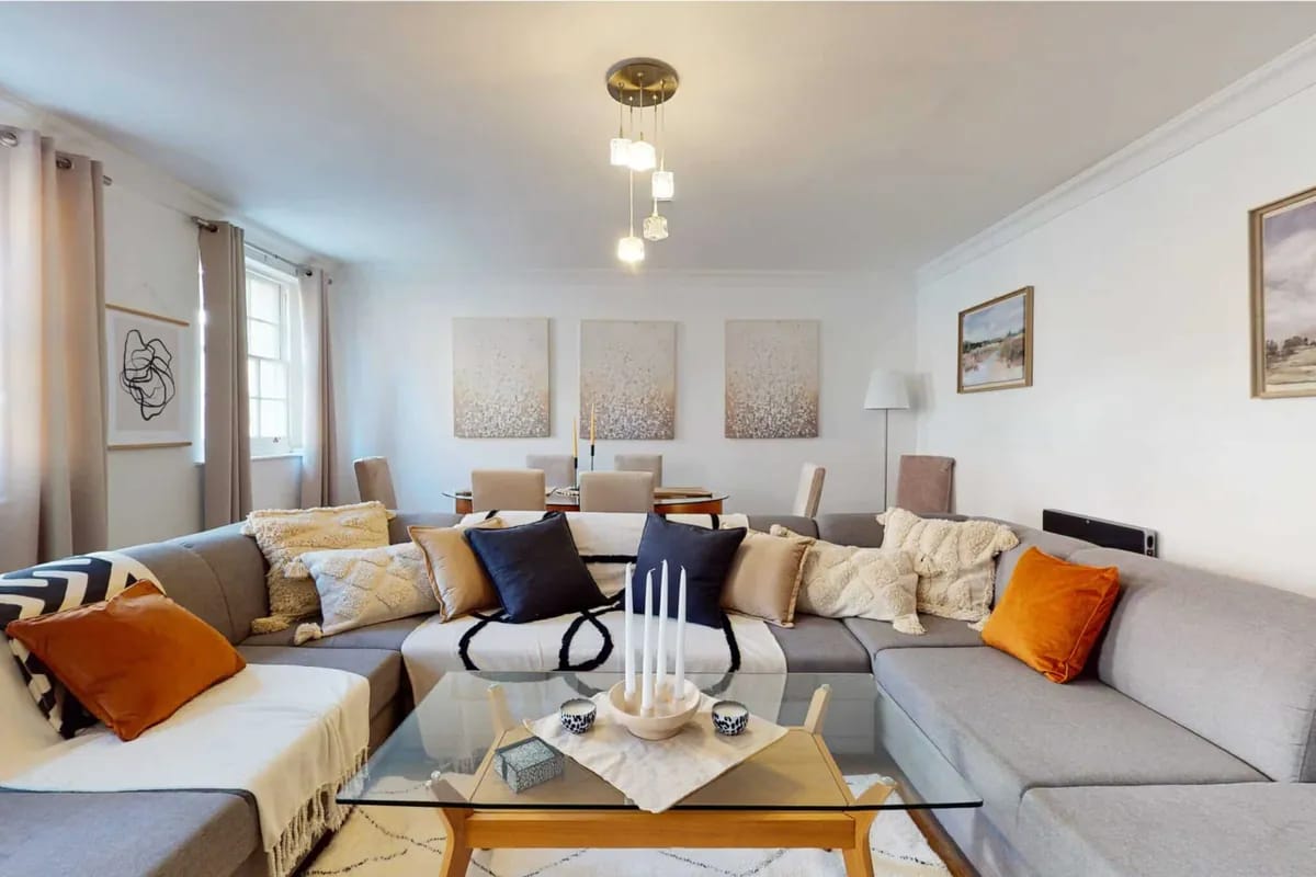 Living and dining room with a corner sofa and three framed prints at 34-36 Clarges Street Mayfair