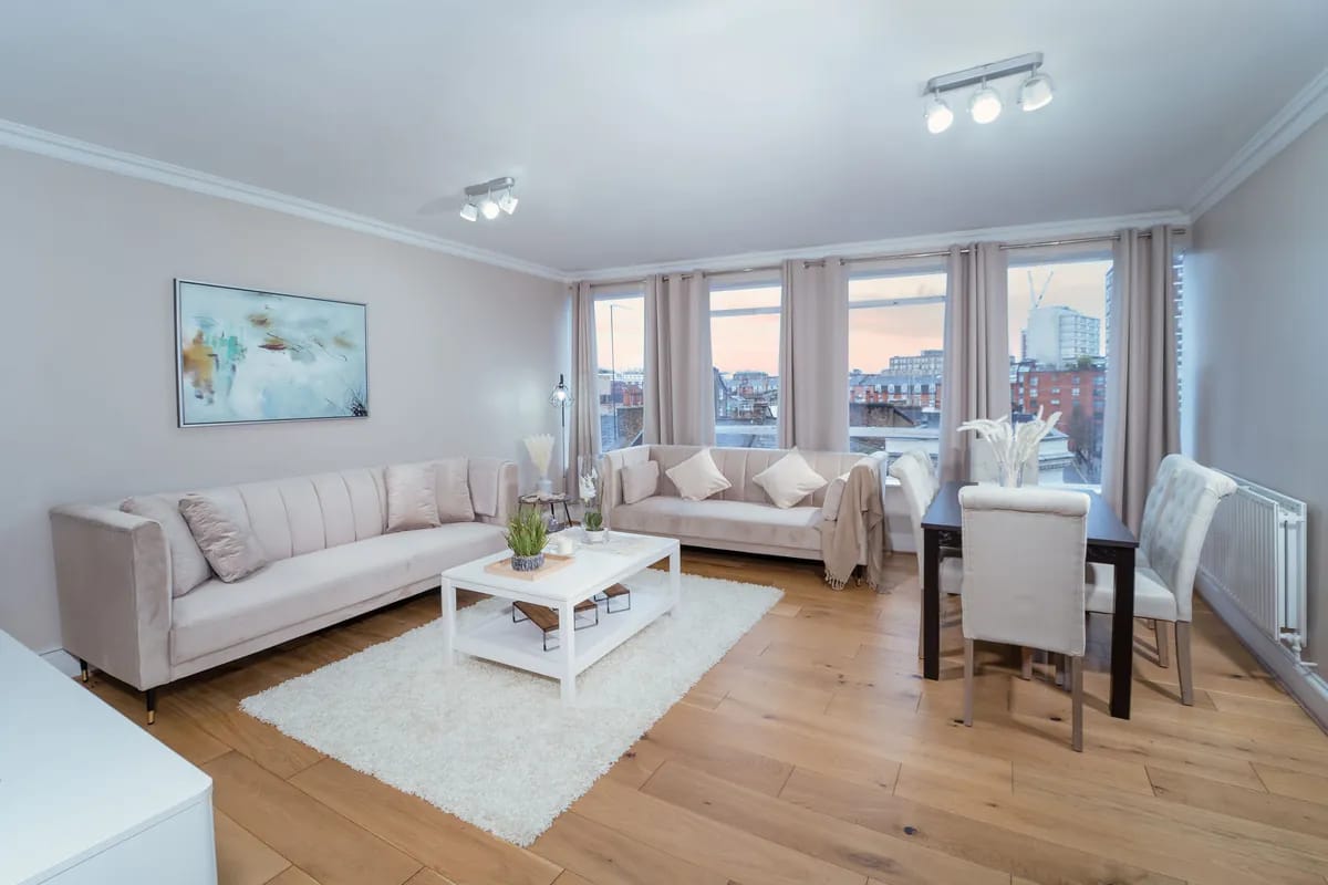 Living and dining room with pale sofas and a rooftop view at dusk at Crawford Place Marylebone