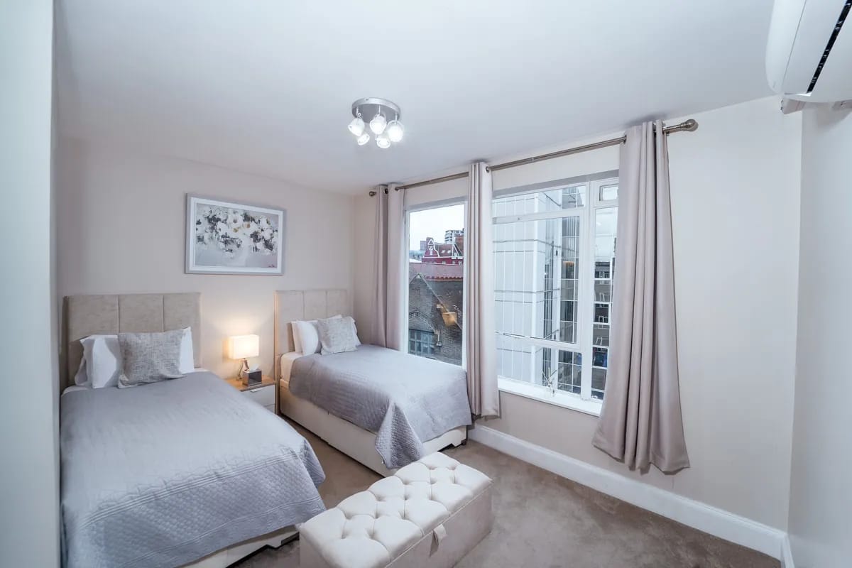 Twin bedroom with two single beds and a tall window at Crawford Place Marylebone